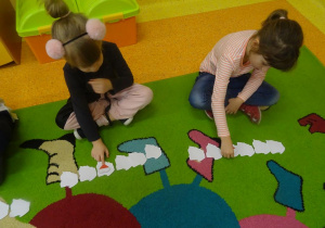 Dwie dziewczynki obracają czwarty z kolej szablon mapy Polski.